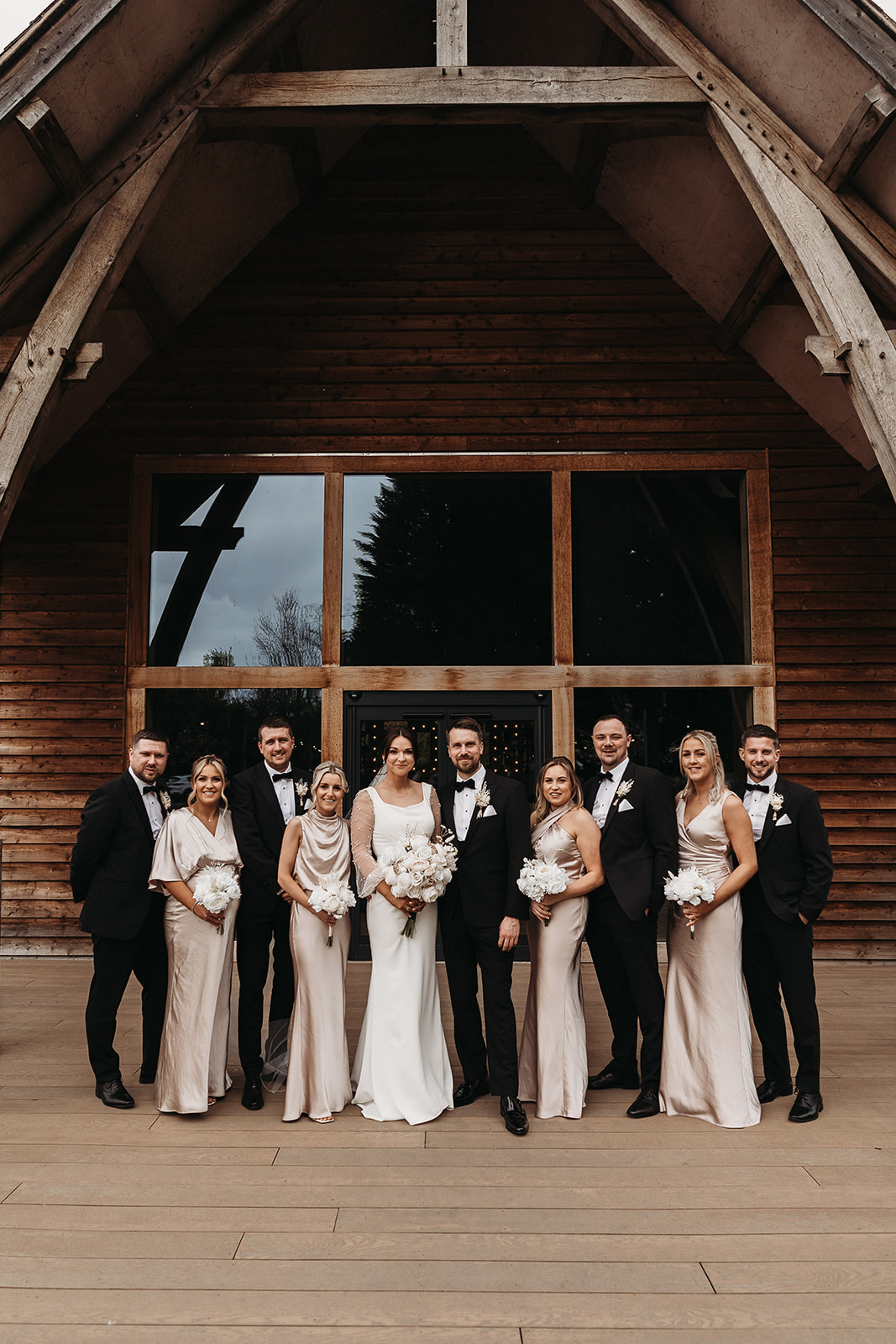 Bridal party and groomsmen standing outside at Shropshire wedding venue, The Mill Barns for group photo