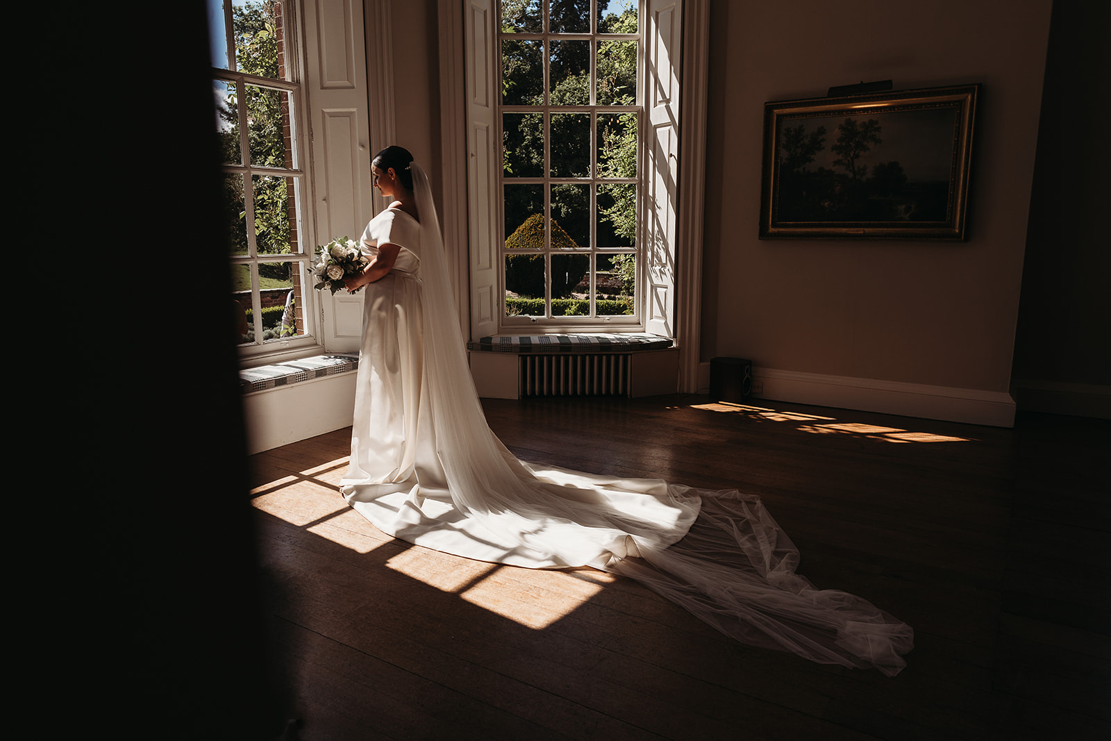 Bride looking out of the window as the natural light shines through at Shropshire wedding venue, Iscoyd Park